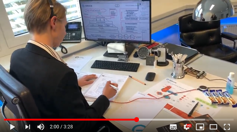 Mann vor Schreibtisch am Laptop schreibt etwas auf.